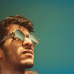 Portrait of a man in sunglasses gazing upward on a clear sunny day.